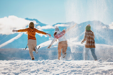 Three happy girls having fun and throwing snow in mountains