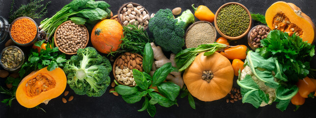 Assortment of seasonal autumn vegetables, cereals and nuts: broccoli, cauliflower, pumpkin, spinach, basil, parsley, ginger, mung bean, quinoa, beans, cashews, almonds, pistachios. Banner