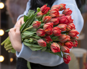 Young woman florist holding big beautiful blossoming mono bouquet of peach ranunculus clooney hanoi...