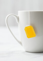 Teabag with yellow blank tag of black tea in white porcelain cup on white