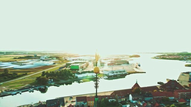 Large golden rooster weather vane on the top of a large medieval church spire. 4K aerial video.