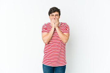 Young cool man laughing about something, covering mouth with hands.