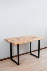 Wooden stylish table made of solid wood with epoxy resin on the background of the floor and wall