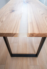 Wooden stylish table made of solid wood with epoxy resin on the background of the floor and wall. Close-up