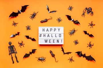 Halloween composition. Black skeletons, bats, spiders, flies, bugs and rats on orange background. Text HAPPY HALLOWEEN, trick or treat party concept. Flat lay, top view