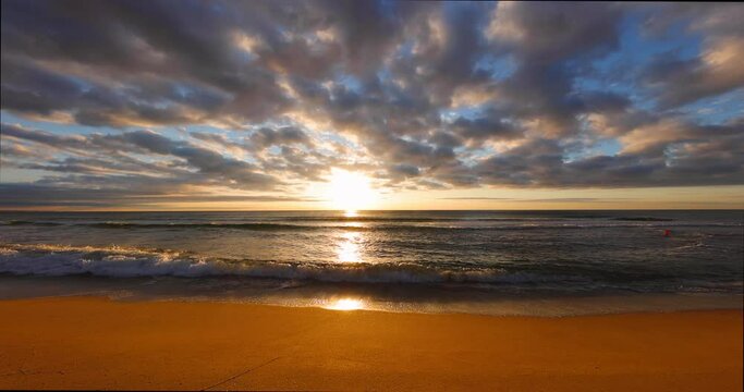Ocean beach sunrise. Golden rising sun and ripple sea waves on the sand.