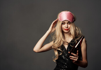 Beautiful blonde with a pink sleep mask and a bottle of beer in her hand