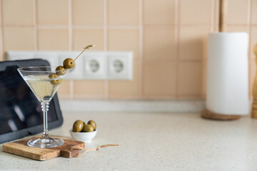 COvid-19 concept - quarantini drink martini via online communication with tablet, kitchen background