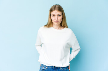 Young blonde woman isolated on blue background sad, serious face, feeling miserable and displeased.