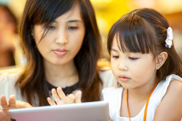 mother and her daughter using computer tablet