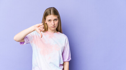 Young blonde woman isolated on purple background showing a dislike gesture, thumbs down. Disagreement concept.