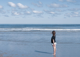 A girl sees a sailboat in the sea