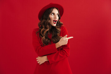 Surprised beautiful woman exclaiming and pointing finger aside