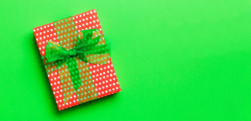 Top view Christmas present box with green bow on green background with copy space