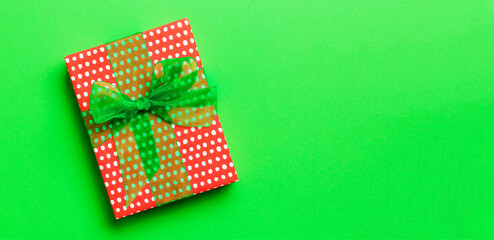 Obraz premium Top view Christmas present box with green bow on green background with copy space