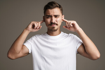 Image of caucasian displeased guy plugging his ears