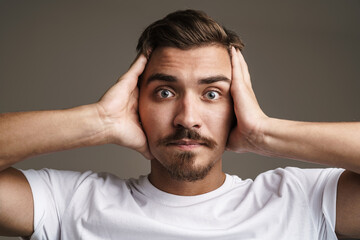 Image of shocked unshaven guy expressing surprise and grabbing her head