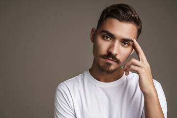 Image of caucasian unshaven guy posing on camera with arms crossed