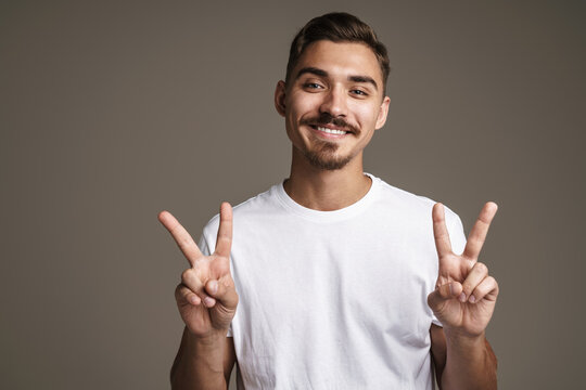 Image of cheerful unshaven guy showing peace sign gesture