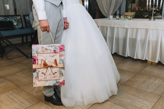 The bride and groom are holding a gift, cardboard packaging with a picture at the wedding ceremony, party.