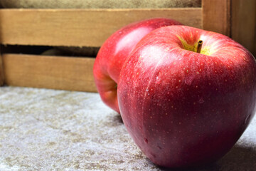 Close up. Red apple with water drops on light stone, in wooden box background, space for text