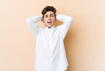Young caucasian man isolated on beige background screaming with rage.