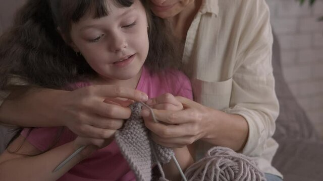 Show to knit. A mother show how to knit t her daughter from wool.