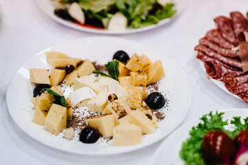 Plate with different cheeses. Serves dinner, food on a festive table at wedding banquet.