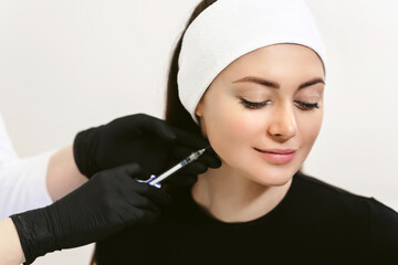 Cosmetology clinic. Face injection concept. Close up beautiful female face and hands in gloves. Beauty treatment with syringe isolated on white