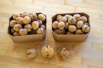 Walnuts on table in hard shells, group of dry ripened fruits cardboard boxes, crop food ingredients ready for cooking