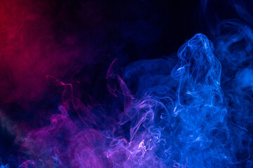 Conceptual image of colorful red and blue color smoke on dark black background.