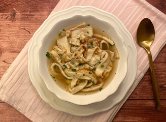Clear soup with strips of pancake and served with parsley.