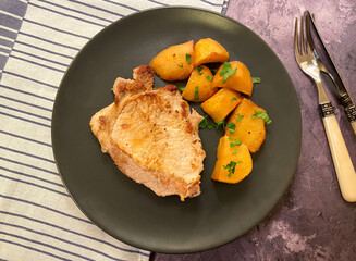 In pan seared pork cutlets also known as pork chops with skillet fried potatoes.