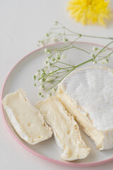 traditional cheese with white mold in the section on a light dining table decorated with flowers. Scandi style