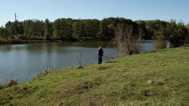 Man fisherman gets a spinning rod from the river. Slow motion.