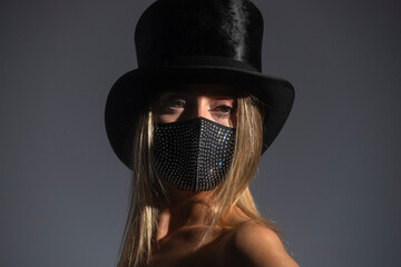 Young woman wearing sparkly face mask and top hat