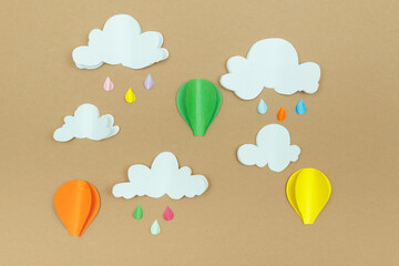 Cardboard clouds, raindrops and air balloons on the beige background. Balloons in the sky with raindrops and clouds.