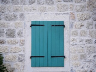 Closed green shutters on a stone wall