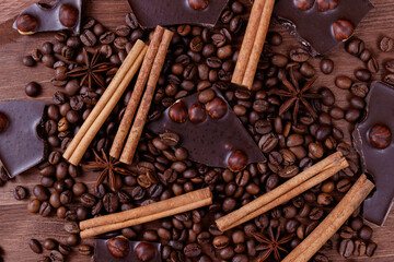 Chocolate bar with nuts on a wooden table with coffee beans and spices. Roasted coffee beans,...