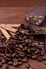 Wafer bars covered with chocolate on a dark wooden background with coffee beans, cinnamon sticks and anise stars. Wafer bars stack. Macro shot.