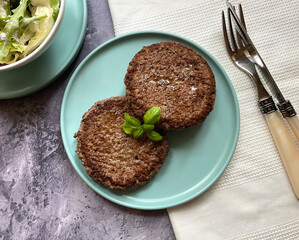 Fried mince patties, also know as rissoles. The side dish is a Greek style salad with colorful vegetables, mixed greens, red onions, cucumber, tomato, crumbly feta cheese and vinaigrette.