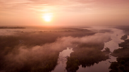 Fototapeta na wymiar amazing aerial view of foggy morning river and colorful trees. drone shot