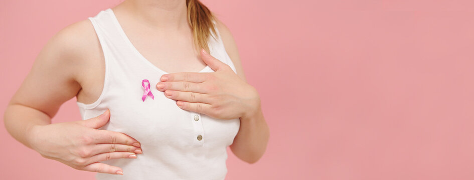 Self examination of the breasts, breast cancer awareness concept. Isolated on pink background. High quality photo