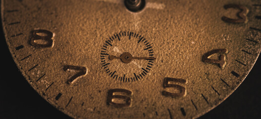 Vintage wall clock on a dark background. Selective focus. Vintage light toning. Grunge style backdrop