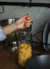 Woman cooking. Closed Glass Jar With Raw Pasta. Woman is going to cook pasta.