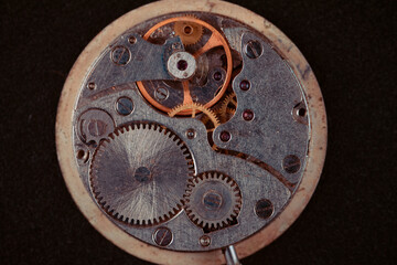 Fototapeta na wymiar Old clockwork mechanism in close-up. Selective focus on macro details. Light vintage toning. Grunge style backdrop