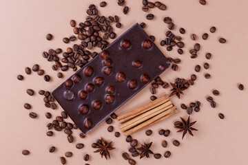 Chocolate bar with nuts on the beige background with coffee beans and spices. Roasted coffee beans,...