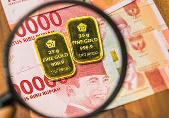 Profile of Fine Gold 25 gram produced by Aneka Tambang, an Indonesian government company, on rupiah money background.