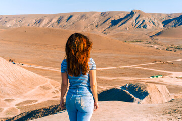 A young woman with long hair stands on the slope of Cape chameleon with an amazing panoramic view...