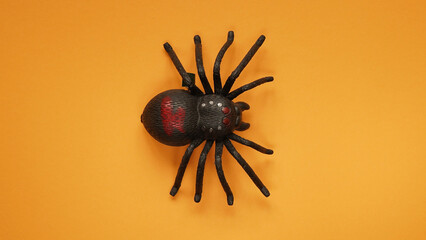 Black clockwork plastic toy spider on a orange background, close up. oncept of celebrating the day of the dead, Halloween.Top view, flat lay,copy space